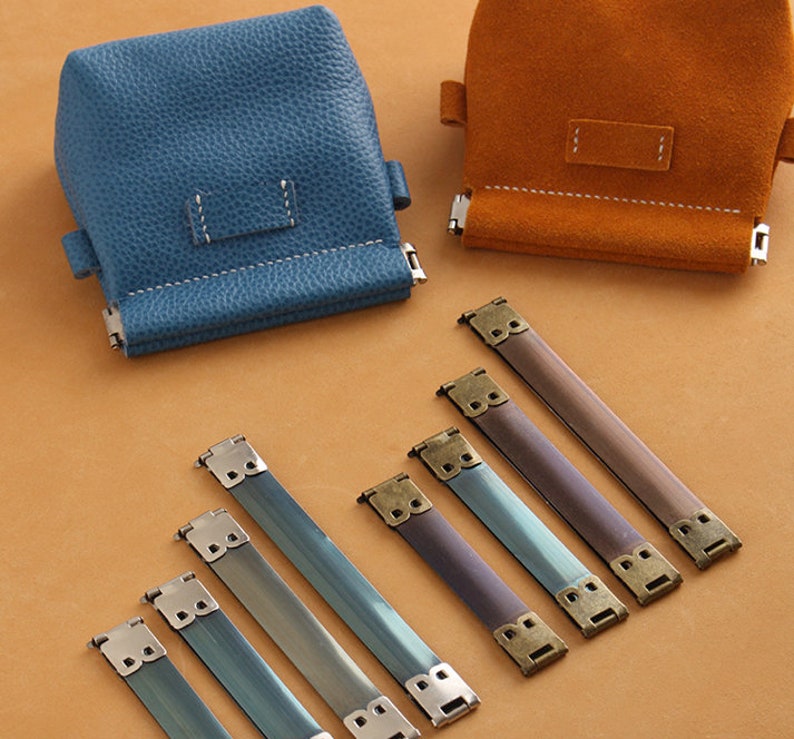 May include: Five metal bag strap buckles with a brass finish and a blue leather bag and a brown leather bag.