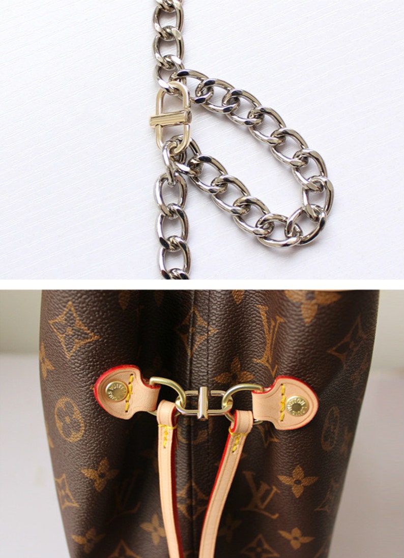 May include: Close-up of a brown leather handbag with a gold metal chain strap. The bag has a brown and beige monogram pattern and a gold metal clasp.