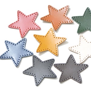 May include: Seven leather star shapes in various colors, including pink, brown, green, yellow, blue, white, and gray. Each star has a stitched border.