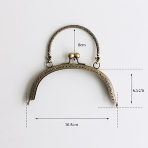 May include: A gold-toned metal purse frame with an ornate design. The frame measures 6.5 inches tall, 16.5 inches wide, and has a handle that is 8 inches long.