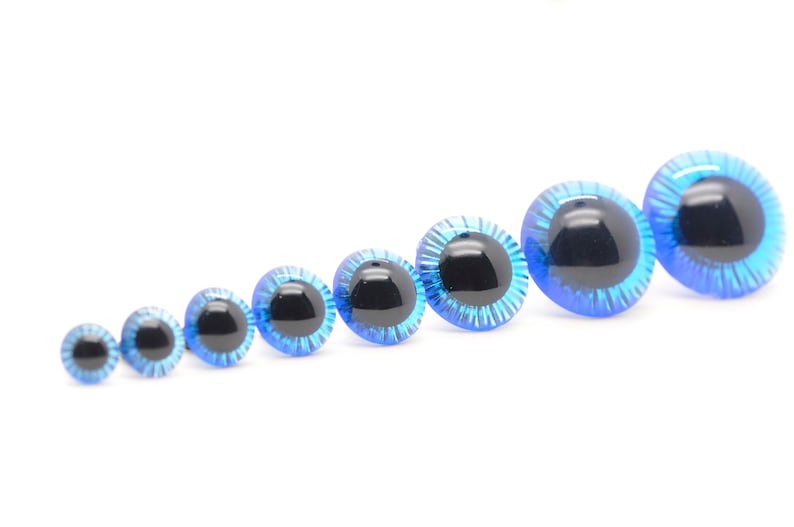 May include: Assortment of blue plastic safety eyes with black pupils, ranging in size from small to large.
