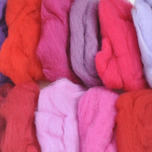 May include: A collection of 10 balls of wool yarn in various shades of pink, red, and purple. The yarn is soft and fluffy, perfect for knitting or crocheting.