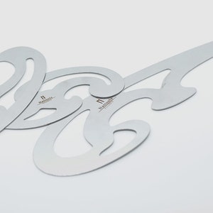May include: Three silver metal stencils for creating decorative patterns. The stencils are shaped like a series of curves and loops. The word "remarkable" is printed on each stencil.