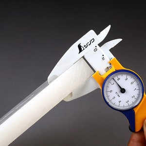 May include: A white and yellow caliper with a blue dial measuring a white cylindrical object. The dial reads 0.1 mm and has markings from 4 to 9.