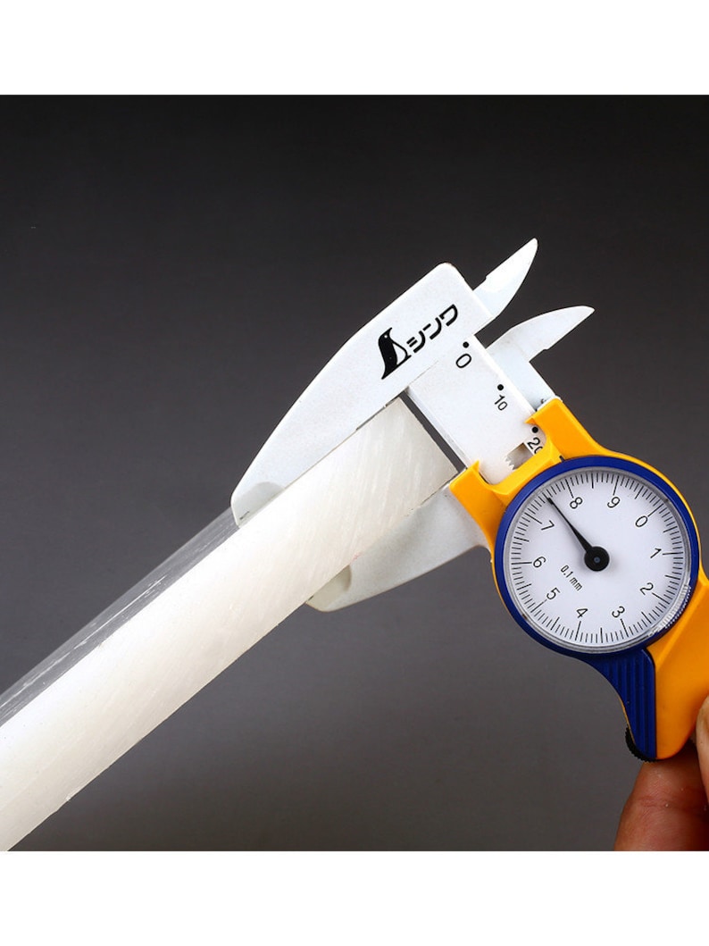 May include: A white and yellow caliper with a blue dial measuring a white cylindrical object. The dial reads 0.1 mm and has markings from 4 to 9.