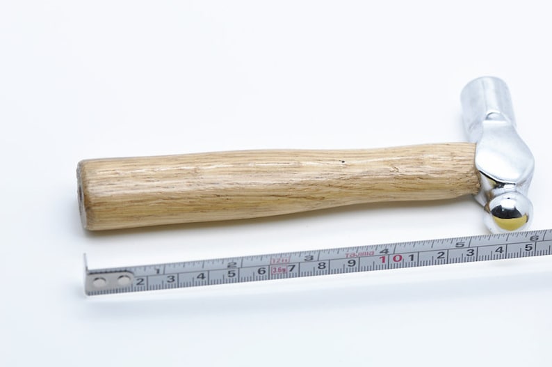 May include: A silver ball-peen hammer with a wooden handle. The hammer is 10.5 inches long and is measured with a ruler.