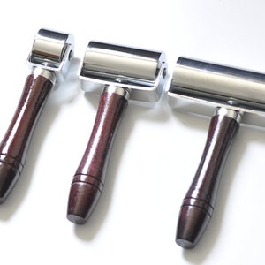 May include: Three chrome-plated leather rollers with wooden handles. The rollers are different sizes.