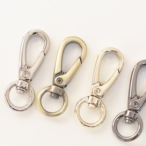 May include: Four metal swivel clasps with a ring on one end. The clasps are in silver, gold, gold, and black.