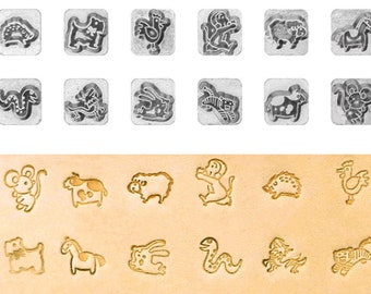 May include: A set of 12 metal stamps featuring animal designs. The stamps are arranged in two rows of six. The top row shows a hedgehog, a dog, a rooster, a monkey, a sheep, and a horse. The bottom row shows a snake, a dragon, a cat, a cow, a bear, and a monkey. The stamps are used to create impressions on leather or other materials.