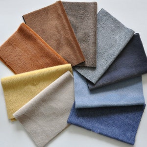 May include: A selection of fabric swatches in various colours and textures, including brown, orange, yellow, beige, grey, blue, and navy.