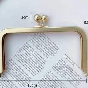 Peut inclure: Un cadre de sac à main en métal doré avec une fermeture à fermoir. Le cadre est rectangulaire, mesurant 15 cm de large et 8,5 cm de haut, avec un petit élément décoratif en haut. Le fermoir mesure 1 cm de large. Idéal pour l'artisanat.