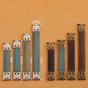 Könnte beinhalten: Sieben Metall-Riemenschnallen in verschiedenen Größen von 8 bis 12 cm. Die Schnallen sind silber und bronzefarben und haben ein dekoratives Design.