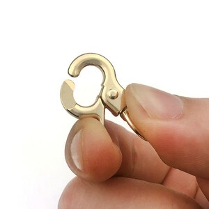 May include: Gold-toned metal swivel clasp with a spring-loaded gate. The clasp is designed for attaching to a bag, purse, or other accessories.