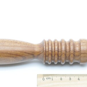May include: A wooden tool with a rounded end and a textured, ridged section. The tool is approximately 7 inches long.