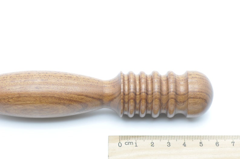 May include: A wooden tool with a rounded end and a textured, ridged section. The tool is approximately 7 inches long.