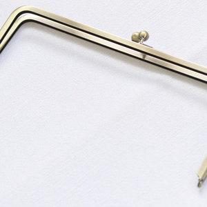 May include: A gold-toned metal purse frame with a double-prong closure.