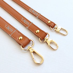 Peut inclure: Trois lanières en cuir marron avec des fermoirs dorés et des clous métalliques. Les lanières mesurent 0,9 cm, 1,4 cm et 1,8 cm de long.