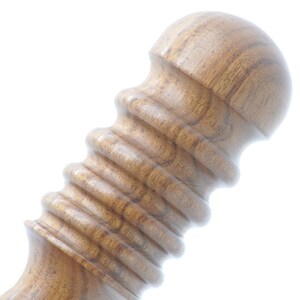 May include: Close-up of a wooden massage roller with a rounded top and a textured, ribbed surface.