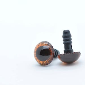 May include: Two brown plastic safety eyes with black plastic backs. The eyes are approximately 2.5 cm in diameter.