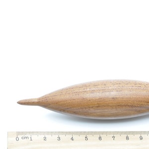 May include: A wooden spindle with a pointed tip and a rounded handle. The spindle is approximately 12 inches long and is made of a light brown wood.
