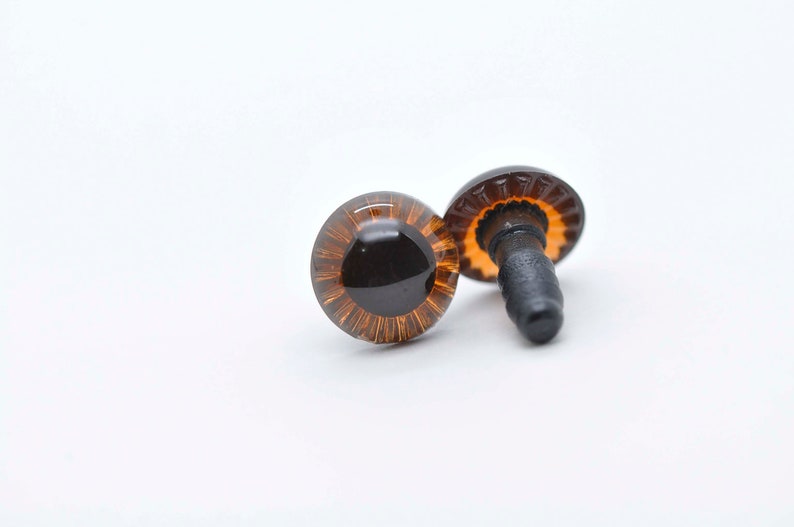 May include: Two brown plastic safety eyes with black pupils and a gold rim. The eyes have a black plastic post on the back for attaching to a stuffed animal or craft project.