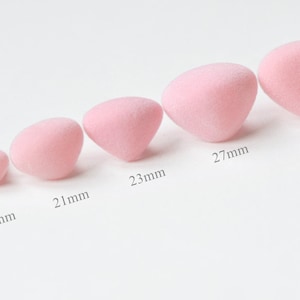 May include: Six pink felt balls of varying sizes, ranging from 12mm to 30mm in diameter. The balls are arranged in a line from smallest to largest.