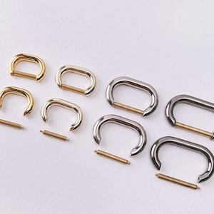 Op de afbeelding: Drie sets metalen D-ringen met een veerbelaste sluiting. Elke set bevat twee D-ringen en een verbindingsstang. De D-ringen zijn verkrijgbaar in de afwerkingen goud, zilver en nikkel.