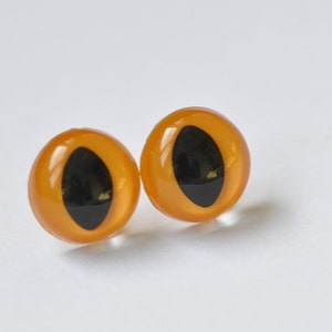 May include: Two orange plastic safety eyes with black pupils. The eyes are round and have a glossy finish.