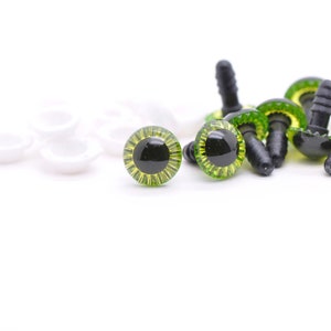 May include: A close-up of green and black plastic safety eyes with white plastic washers. The eyes are used for craft projects and are ideal for adding a whimsical touch to stuffed animals, dolls, and other creations.