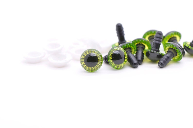 May include: A close-up of green and black plastic safety eyes with white plastic washers. The eyes are used for craft projects and are ideal for adding a whimsical touch to stuffed animals, dolls, and other creations.