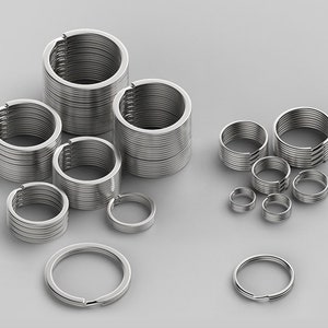 以下が含まれることがあります： さまざまなサイズのシルバーキーリング。キーリングは金属製で、積み重ねられています。一部のキーリングは小さく、大きなキーリングの周りに散らばっています。