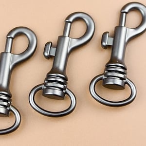 Puede incluir: Tres mosquetones giratorios de metal plateado con cierre de resorte. Los mosquetones tienen un lazo redondo en un extremo y un gancho giratorio en el otro extremo.