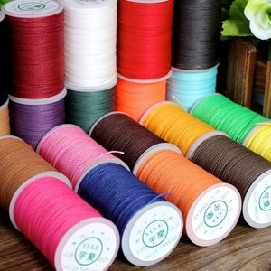 May include: Assortment of spools of waxed thread in various colors, including black, red, white, green, blue, orange, yellow, brown, and pink. The spools are labeled with the text "宇樂" in Chinese characters.