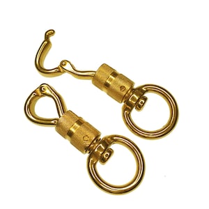 Op de afbeelding: Twee goudkleurige metalen karabijnhaken met een draaibare lus aan het ene uiteinde en een veerbelaste sluiting aan het andere uiteinde.