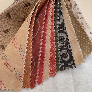May include: A stack of fabric squares in various shades of brown, red, and green with different patterns. The fabric squares are arranged in a fan shape.