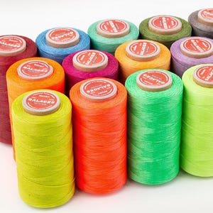 May include: A collection of spools of colorful waxed thread, each with a red label that reads "GALACES".