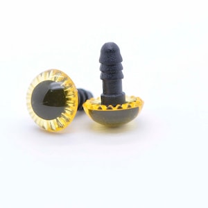 May include: Two yellow plastic safety eyes with black pupils and a black plastic post on the back. The eyes are designed for use in crafts and stuffed toys.