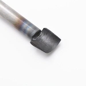 May include: A close-up of a metal tool with a rounded, flat tip. The tool is silver with a blue and brown tint.
