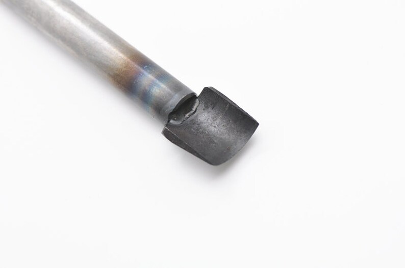 May include: A close-up of a metal tool with a rounded, flat tip. The tool is silver with a blue and brown tint.