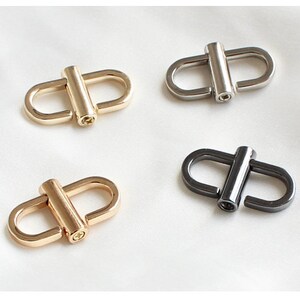 May include: Four metal swivel clasps in two finishes: gold and black. The clasps are oval-shaped with a cylindrical bar in the center.