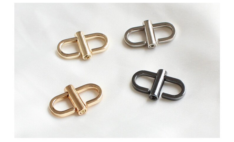 May include: Four metal swivel clasps in two finishes: gold and black. The clasps are oval-shaped with a cylindrical bar in the center.