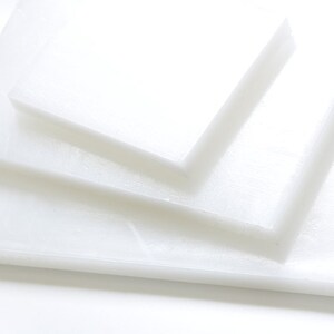 May include: Stack of three white plastic cutting boards of different sizes.
