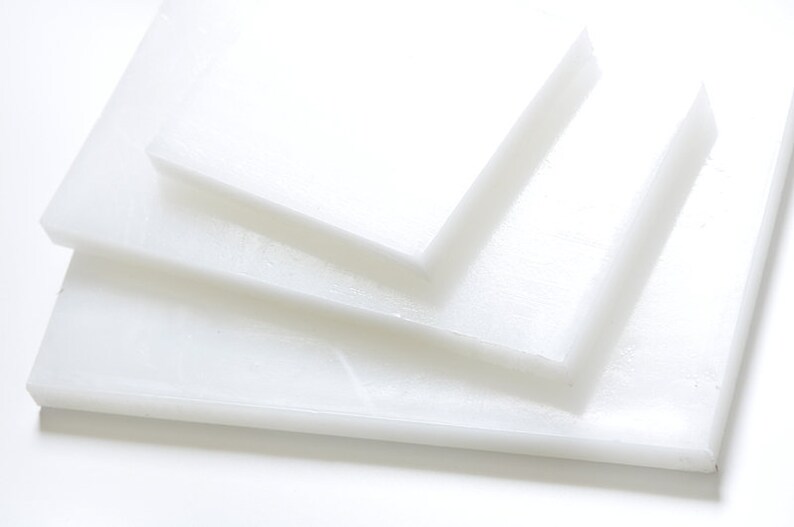 May include: Stack of three white plastic cutting boards of different sizes.