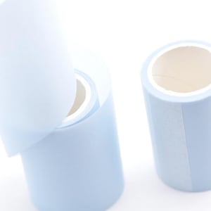 Könnte beinhalten: Drei Rollen hellblaues Klebeband werden vor weißem Hintergrund gezeigt. Eine Rolle hat einen abgezogenen Abschnitt, der den inneren Kern freilegt. Die anderen beiden Rollen sind intakt und zeigen die hellblaue Farbe des Klebebands und den weißen Kern.