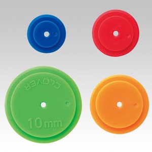May include: Four plastic circle-shaped sewing tools in different colours: blue, red, green and orange. The green tool has the text "CLOVER 10 mm" printed on it.