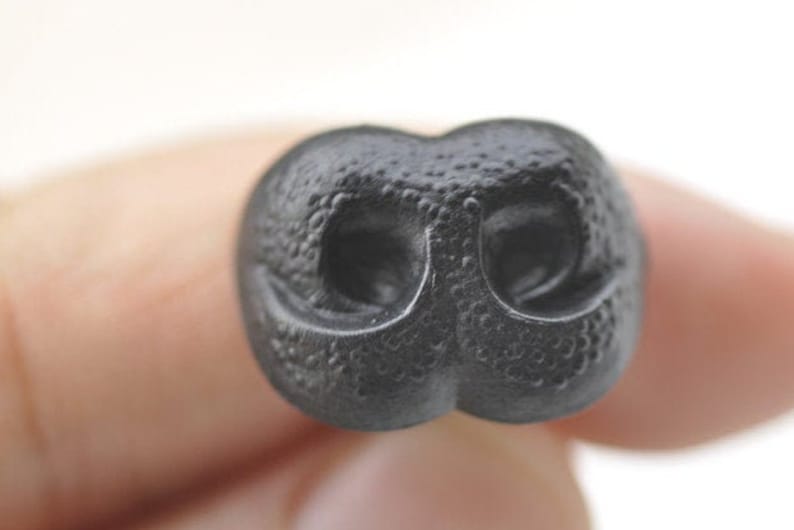 K&ouml;nnte beinhalten: Eine schwarze Plastiktiernase mit strukturierter Oberfl&auml;che. Die Nase hat zwei Nasenl&ouml;cher.