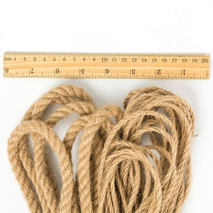 May include: A close-up of a pile of natural brown jute twine, with a wooden ruler measuring 20 centimeters in length.