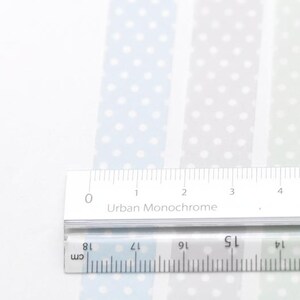 May include: A ruler with centimetre markings, measuring up to 18 cm, is placed over a patterned paper. The paper features vertical stripes in pastel colours with white polka dots. The text "Urban Monochrome" is visible.