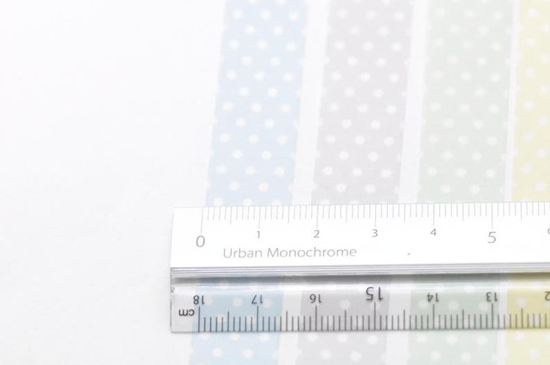May include: A ruler with centimetre markings, measuring up to 18 cm, is placed over a patterned paper. The paper features vertical stripes in pastel colours with white polka dots. The text "Urban Monochrome" is visible.