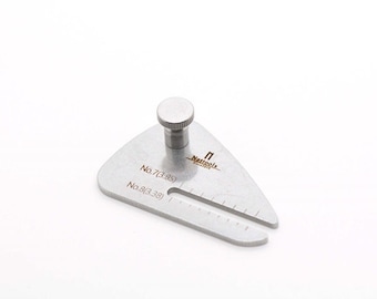 May include: A silver metal gauge with a knob on top and markings for sizes 7 (3.89) and 8 (3.38). The gauge is labelled "Nattools" and is designed for measuring.